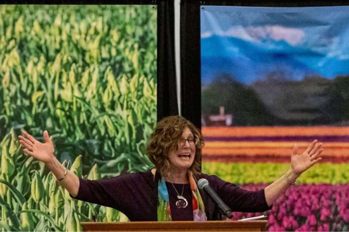 Woman speaking at Tulip Festival with vibrant tulip backgrounds.