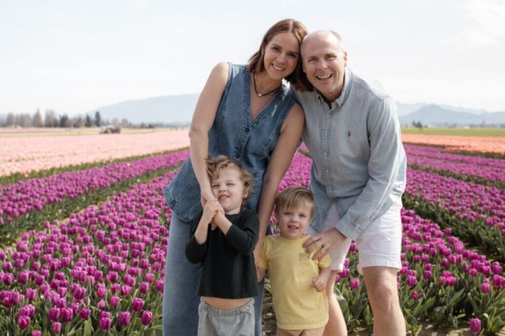 A mother, father, and their two small children pose as a family in front of rows of colorful tulips at the Skagit Valley Tulip Festival.