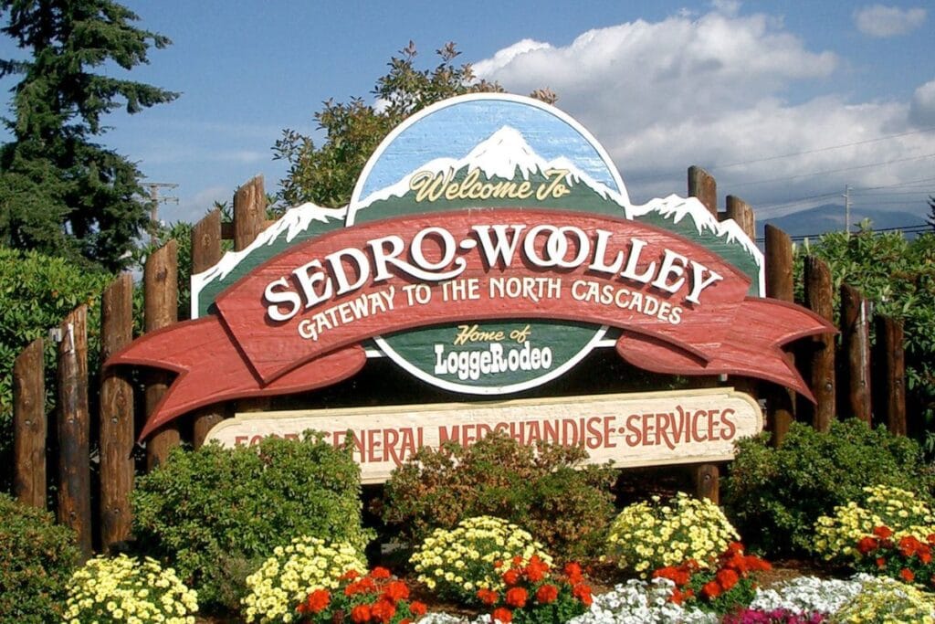 Welcome to Sedro-Woolley sign surrounded by flowers, gateway to the North Cascades near the Skagit Valley Tulip Festival.