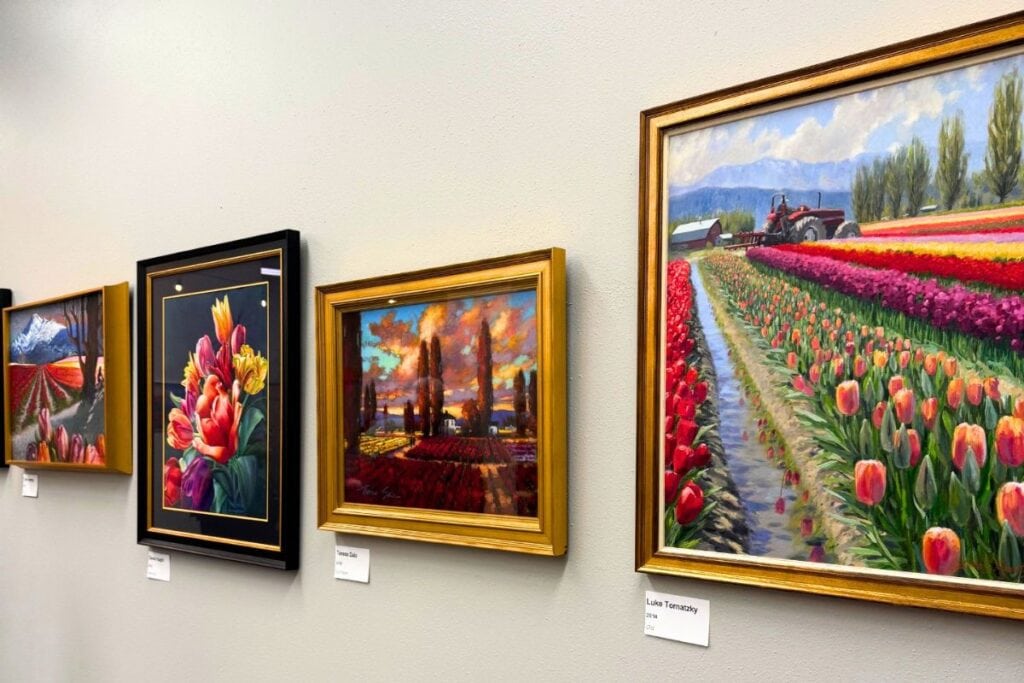 Framed paintings of tulip fields and Skagit Valley landscapes displayed at the Tulip Festival Art Exhibit.